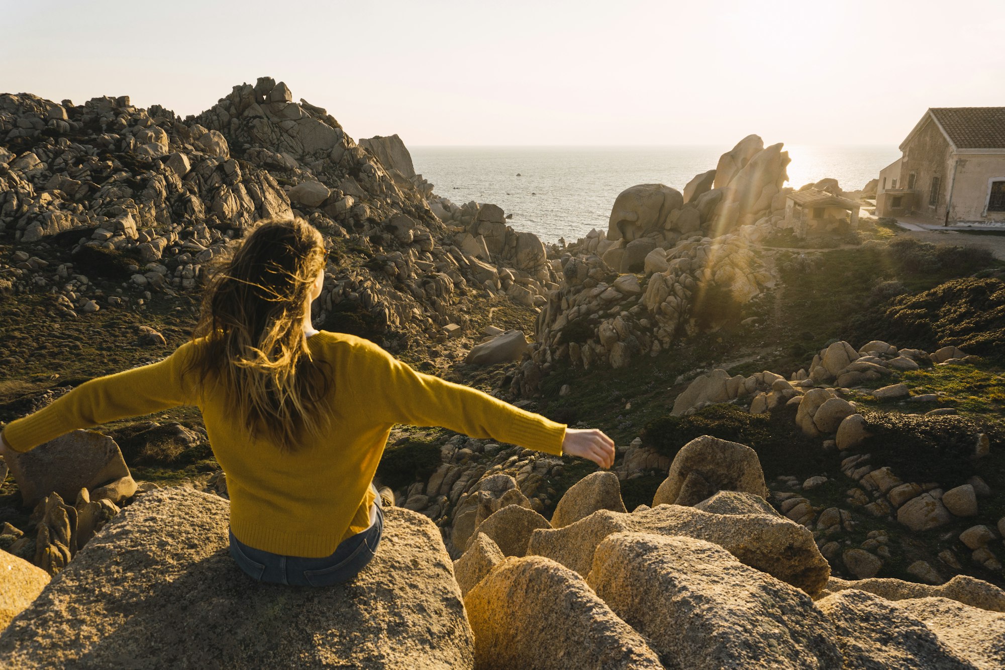 Italy, Sardinia, woman on a hiking trip sitting on rock at the coast Italy, Sardinia, woman on a hiking trip sitting on rock at the coast