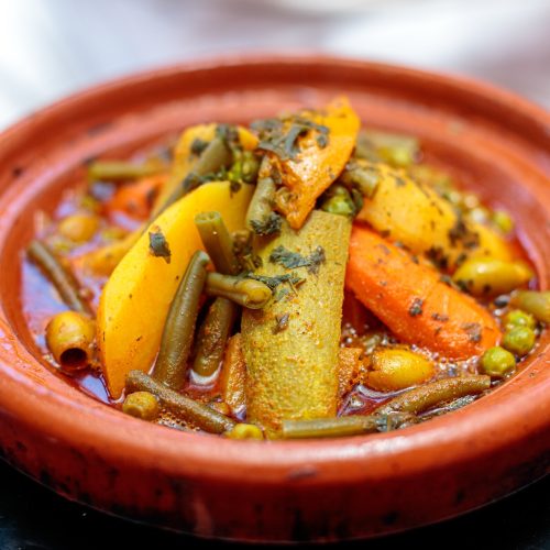 High angle closeup shot of a tajine dish in a clay plate in a blurred background