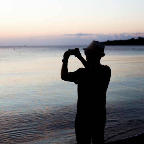 man taking photos of sunset with mobile phone