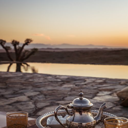 Vertical closeup shot of a typical Moroccan mint tea set on the table in Agafay desert, Marrakech
