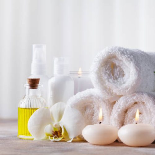 Spa, beauty treatment and wellness background with massage pebbles, orchid flowers, towels, cosmetic products and burning candles. Copy space for text.